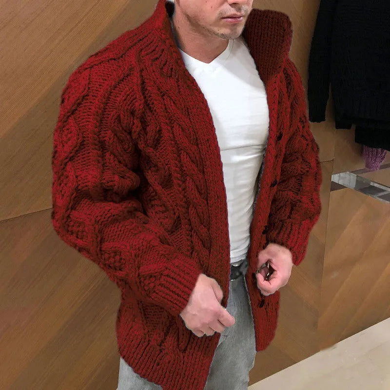 Man wearing a red knitted cardigan over a white shirt in an indoor setting.