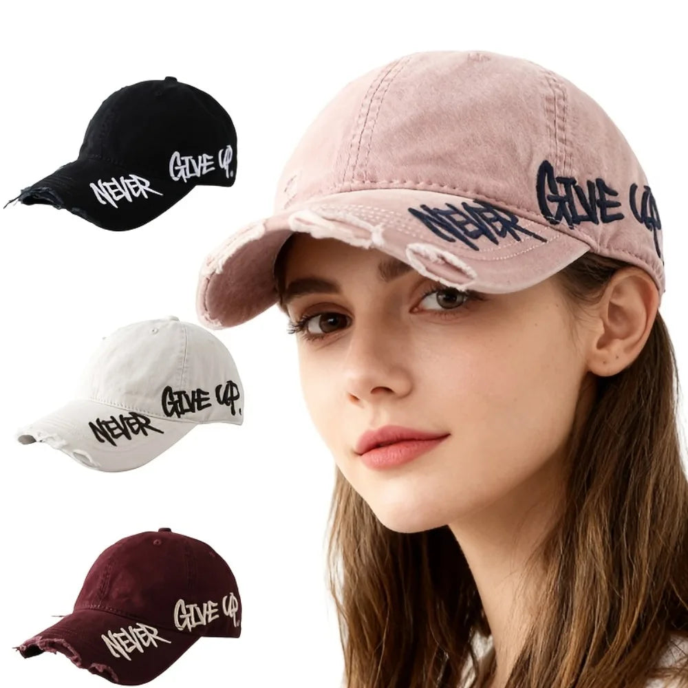 Woman wearing a pink cap with 'Never Give Up' text, surrounded by black, white, and maroon caps.