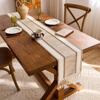 Dining table set with a runner, plates, cups, and books in a home setting.