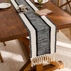 Black and white patterned table runner on a wooden table with a cup and saucer.