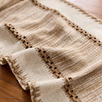 Close-up of a textured beige fabric with intricate stitching on a wooden surface