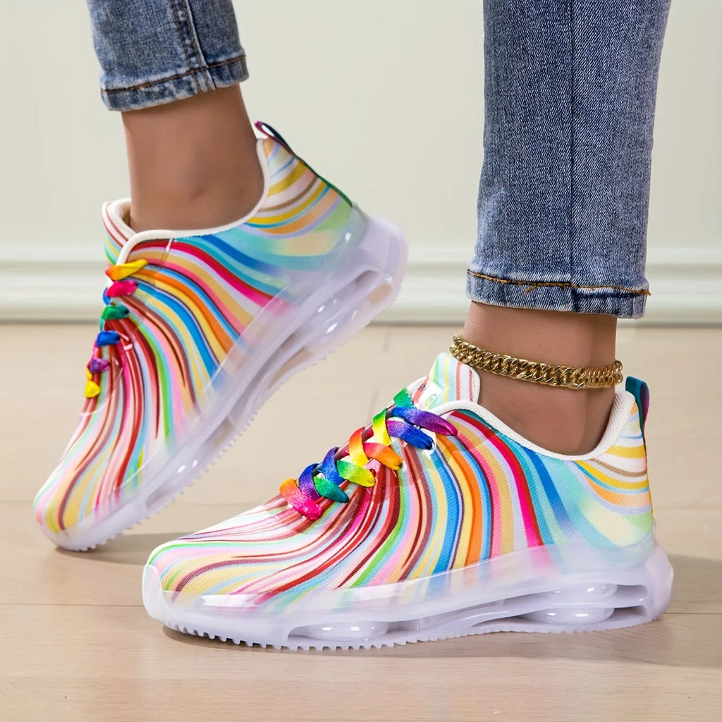 Colorful rain boots with rainbow patterns worn by a person on a light wooden floor.