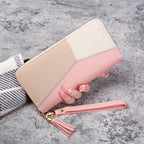 Two-tone wallet with beige and pink colors held by a hand on a gray surface.