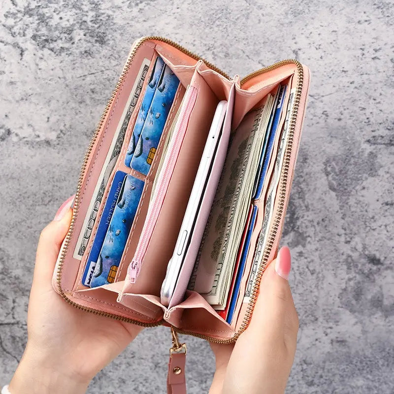 Open pink wallet with various cards and a phone on a gray textured background