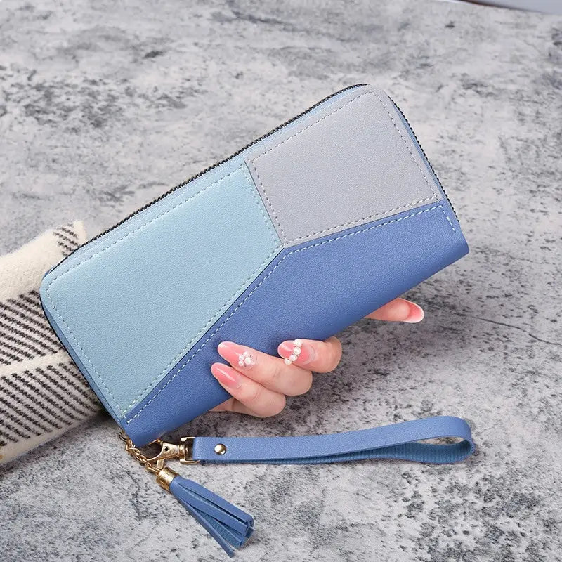 Blue and gray wallet with a wrist strap held by a hand on a gray surface