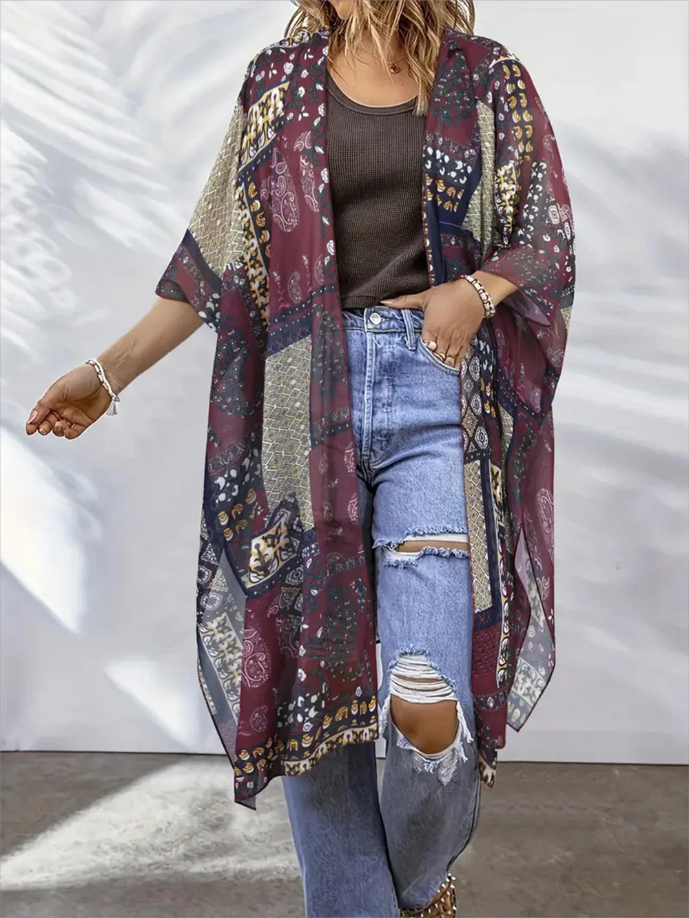 A woman models a lightweight open-front kimono cardigan with a bohemian multicolor patchwork print. The cardigan features a mix of deep burgundy, beige, navy, and gold patterns.