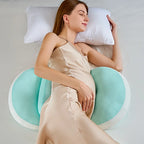 Woman lying on a bed with a green and white body pillow.