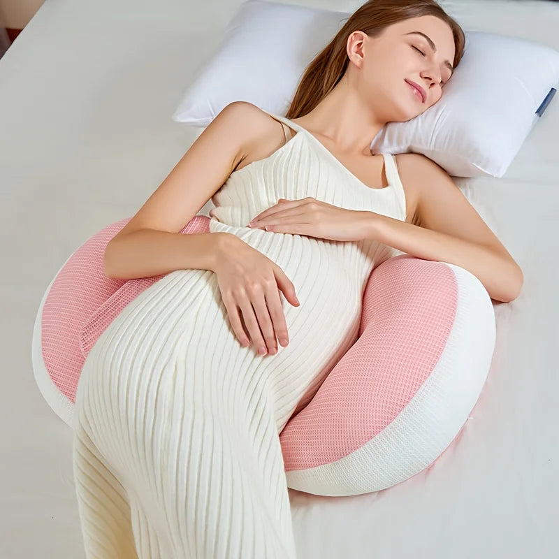 Woman lying on a pink and white U-shaped pillow, possibly during pregnancy.
