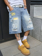 A person wearing light-wash distressed denim shorts with yellow and white graphic patches, a white t-shirt, white socks, and tan lace-up boots, standing on a gray tiled floor.