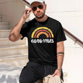 A man wearing a vintage black t-shirt with a retro rainbow graphic and the text 'GOOD VIBES' in white, sitting on outdoor stone steps.