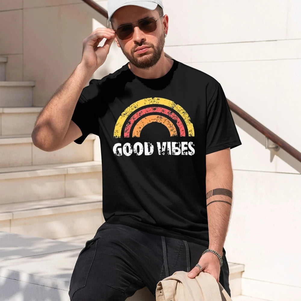 A man wearing a vintage black t-shirt with a retro rainbow graphic and the text 'GOOD VIBES' in white, sitting on outdoor stone steps.