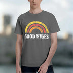A man wearing a dark gray t-shirt with a distressed retro rainbow graphic and the text 'GOOD VIBES' printed in white.