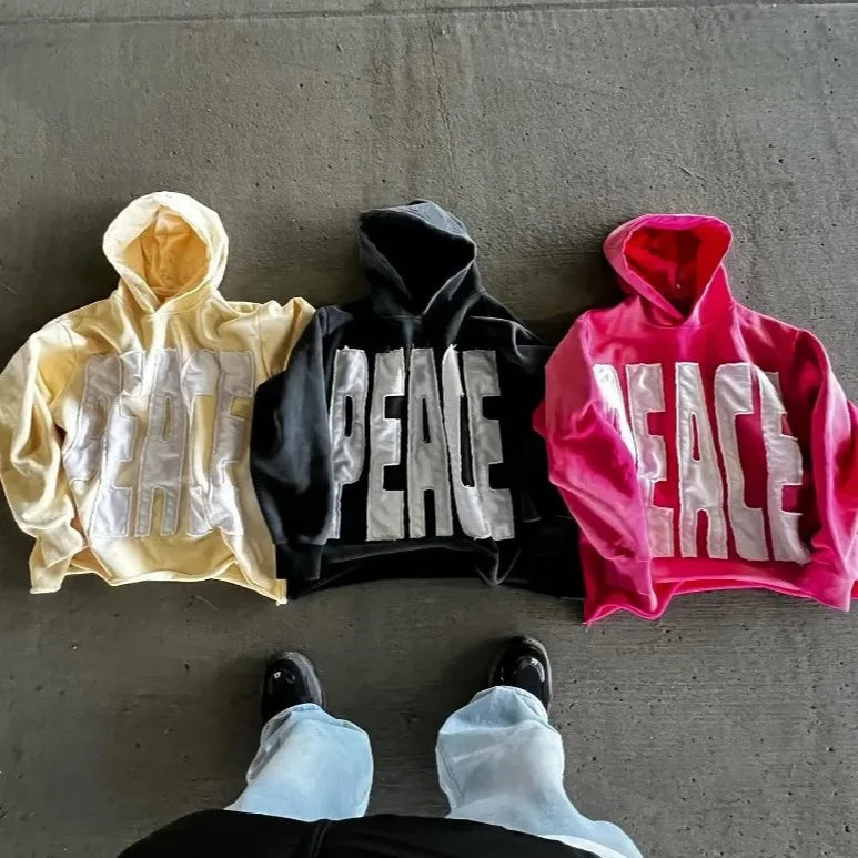 Three hoodies with 'PEACE' text on a concrete floor.