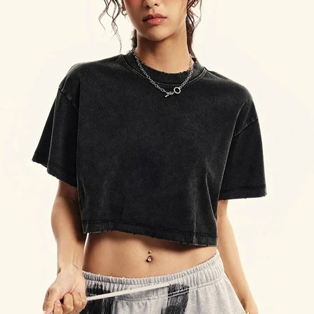 Person wearing a black crop top and gray sweatpants on a beige background