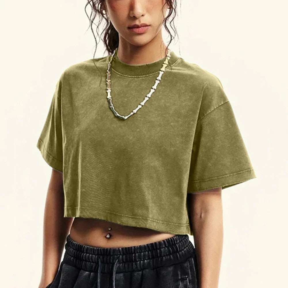 Person wearing a green crop top and black pants against a plain background