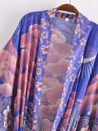 A lightweight open-front kimono-style cardigan draped on a wooden hanger, featuring a vibrant purple and pink floral cloud print with celestial and wave motifs.