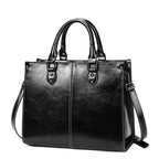Black leather handbag with shoulder strap on a white background