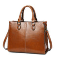 Brown leather handbag with a shoulder strap on a white background
