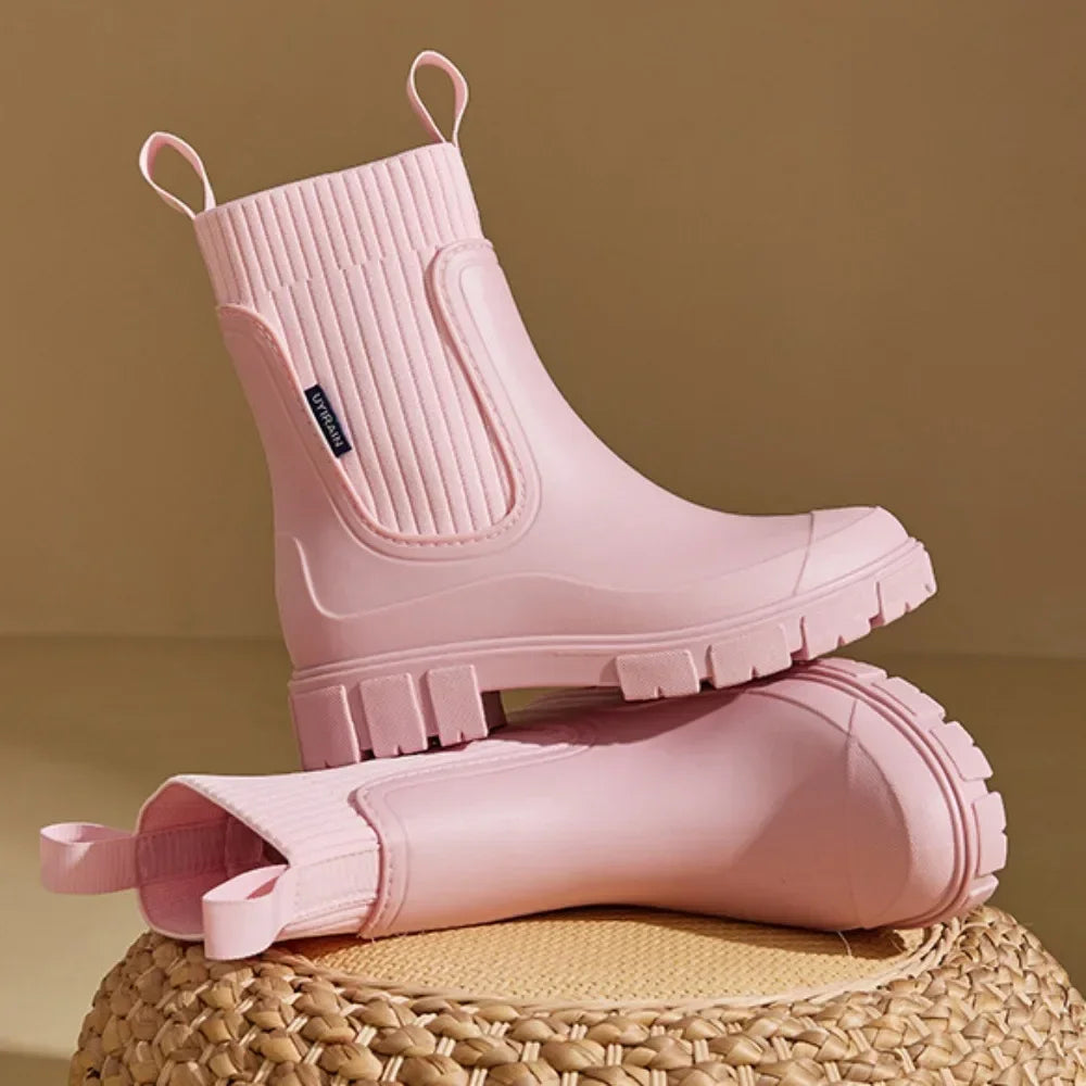 Pink rubber boots stacked on a woven surface with a beige background
