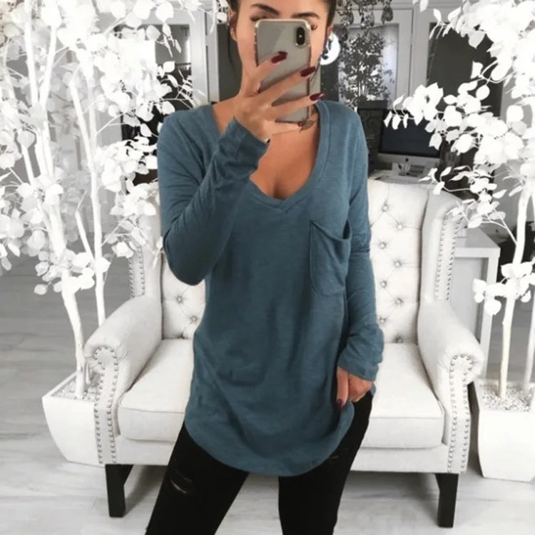 A woman wearing a loose, long-sleeve blue-gray top super long in the backside  rear.