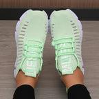 Light green women's running walking casual sneakers shoes worn on a wooden floor.