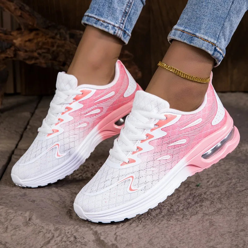 Pink and white sneakers worn with rolled-up jeans on a stone surface.
