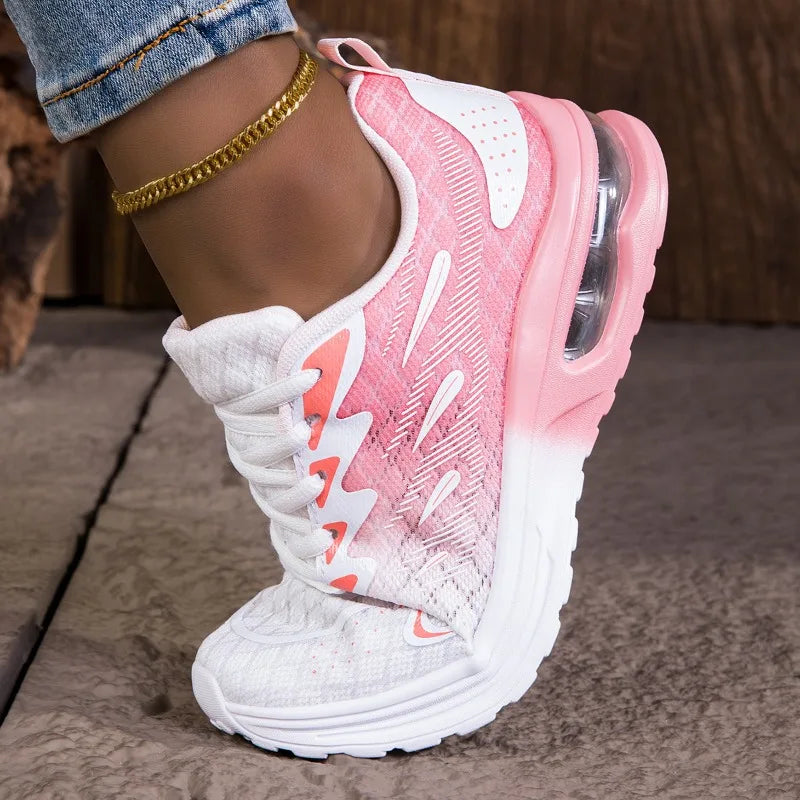 Pink and white sneaker worn on a foot with denim jeans and gold anklets.