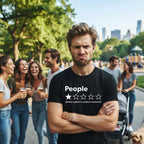 A man in a black graphic t-shirt stands in a sunny park with friends in the background. The t-shirt features a white graphic that says 'People' with one star out of five and the text 'Absolute nightmare, would not recommend.