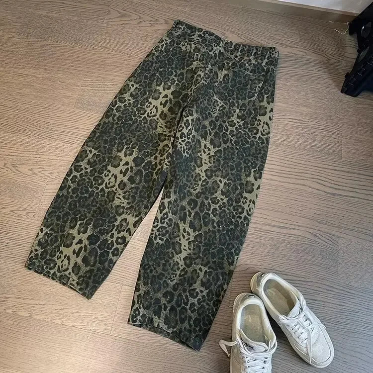 Leopard print pants on a wooden floor with white sneakers beside them.